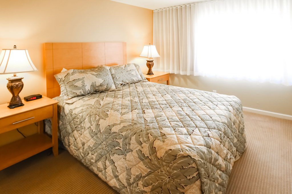 Bedroom unit showcasing queen bed, and side tables with lamps.