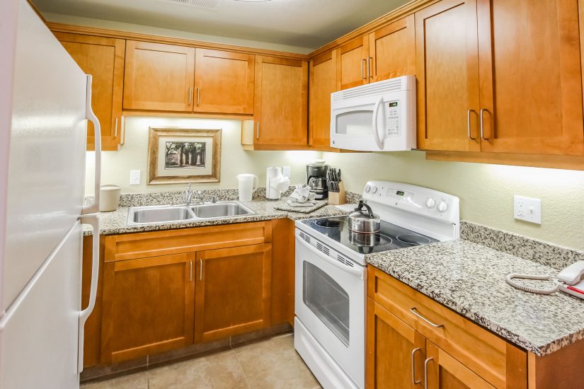 Photo of kitchen showcasing microwave oven, range/oven, double sinks, refrigerator, countertops and cabinets.